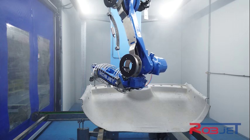 Blauer Roboter mit Schneidkopf über einem hellen Dachhimmelbauteil in einer geschlossenen Robjet-Zelle
