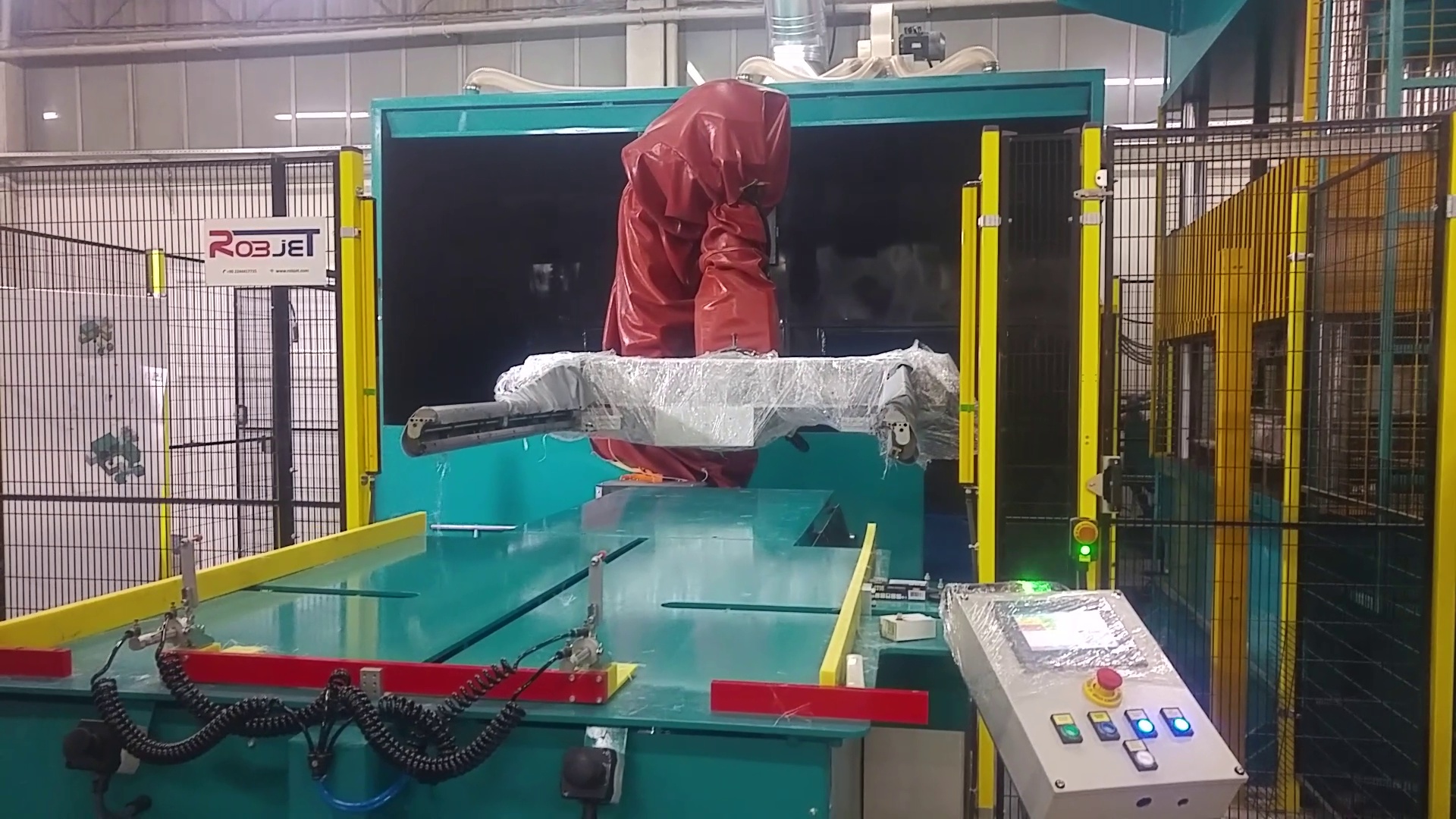 Roboter mit roter Schutzhülle und bauteilspezifischer Aufnahme in einer Robjet-Anlage