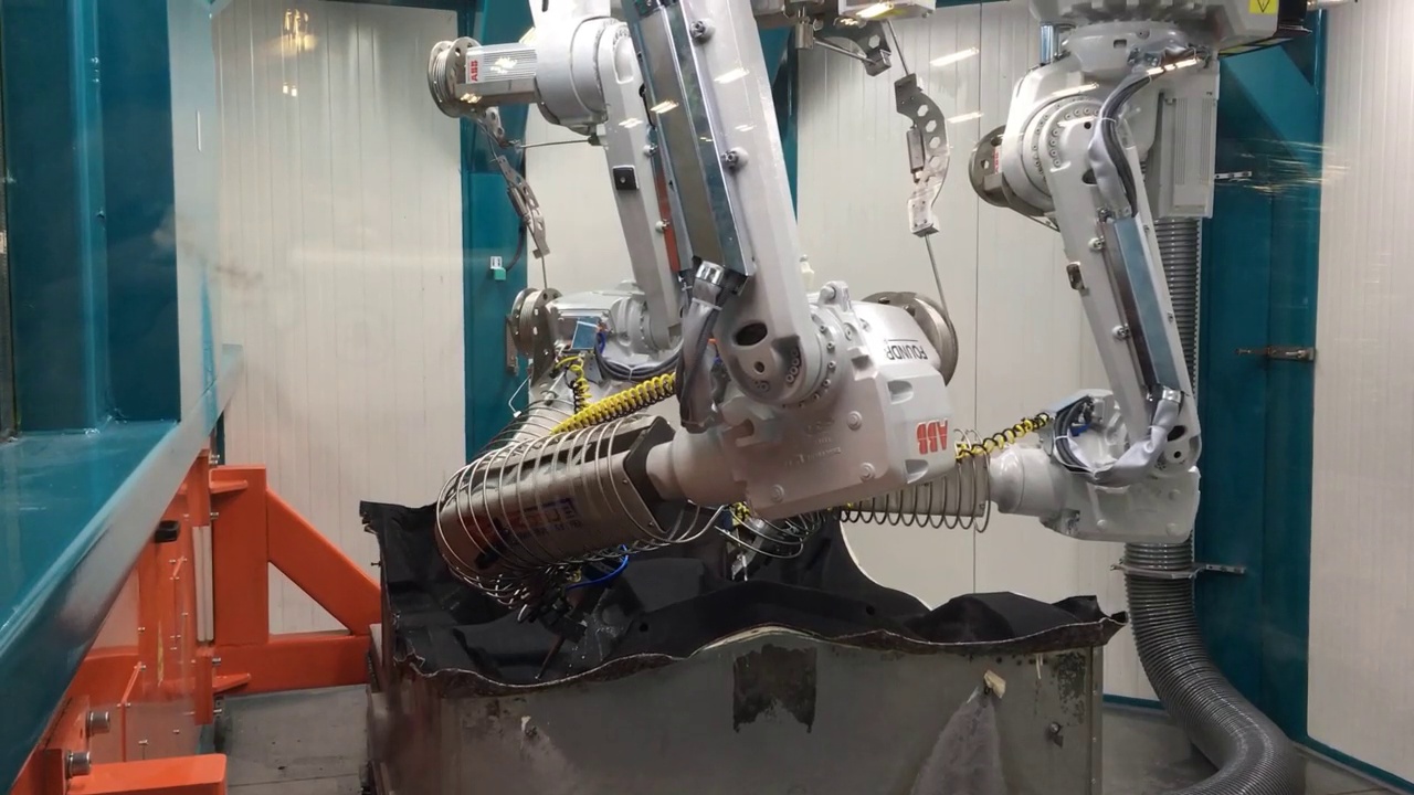ABB-Roboter bearbeiten ein geformtes Teppichbauteil in einer gemeinsamen Schneidzelle